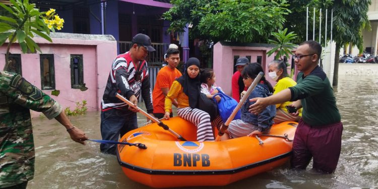 Tim BPBD Kota Surakarta mengevakuasi warga menggunakan perahu karet akibat banjir di wilayah Kota Surakarta, Jawa Tengah, Jumat (17/2). FOTO: BPBD Kota Surakarta